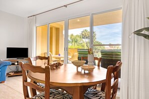 A dining area with a round table, chairs, and a television.