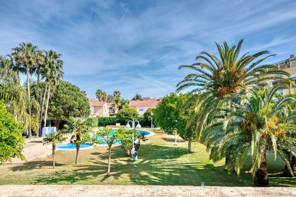 A pool surrounded by palm trees and a building with a red roof.