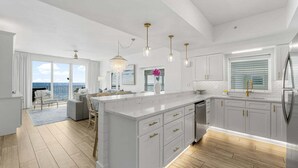 Una cocina moderna con una isla grande, armarios blancos y electrodomésticos de acero inoxidable.