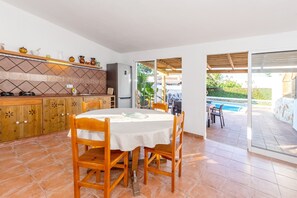 Una cucina con tavolo e sedie, un frigorifero e vista su una piscina.