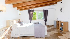 Ein Schlafzimmer mit einem Bett, einem Fenster mit Vorhängen, einem Bücherregal und einer Steinwand.