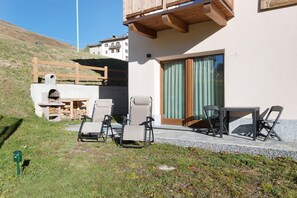 Un espace extérieur moderne aménagé avec une table et des chaises, un foyer et une terrasse en bois.
