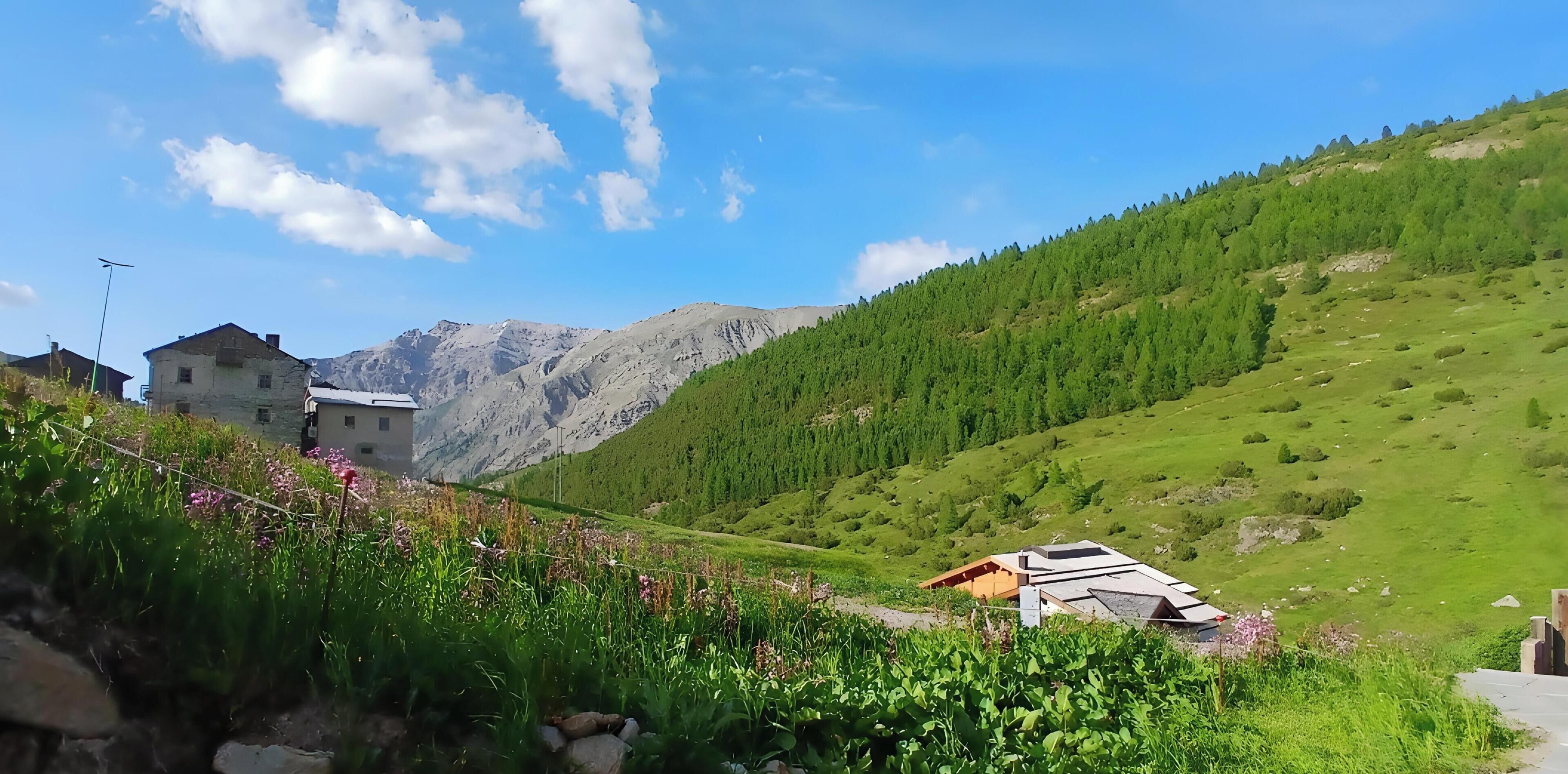A mountainous landscape with a building and a small structure with a sloped roof.