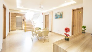 Un moderno vestíbulo de hotel con mostrador de recepción, zona de comedor con sillas, una escalera y un cuadro en la pared.