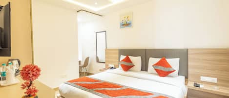 A hotel room with a large bed, a bedside table with a lamp, a small potted plant, and a painting on the wall.