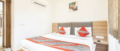 Quarto de hotel moderno com uma cama grande, uma cabeceira de madeira e uma pequena mesa de cabeceira.
