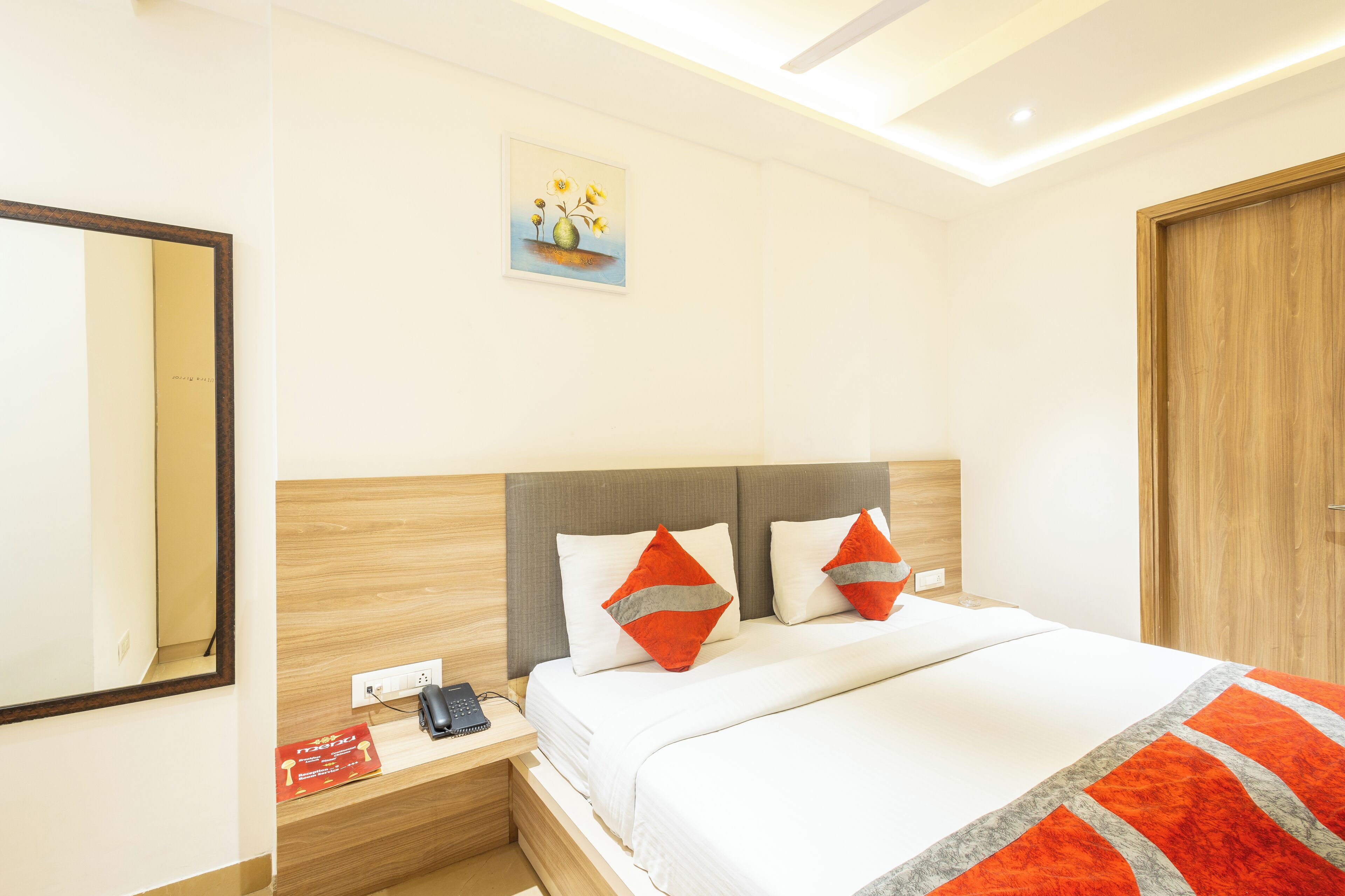 A hotel room with a bed, nightstand, and a painting on the wall.