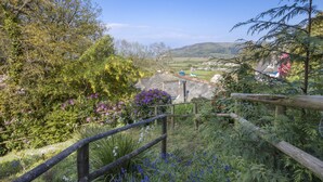 A rural landscape with a wooden fence, lush greenery, and a distant view of houses. - Little Hanger, Porlock (Porlock)