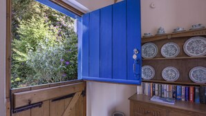 A room with a wooden door, a blue cabinet, and a shelf with plates and books. - Little Hanger, Porlock (Porlock)