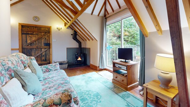 A cozy room with a wooden ceiling, a fireplace, a sofa, and a television. - Little Hanger, Porlock (Porlock)