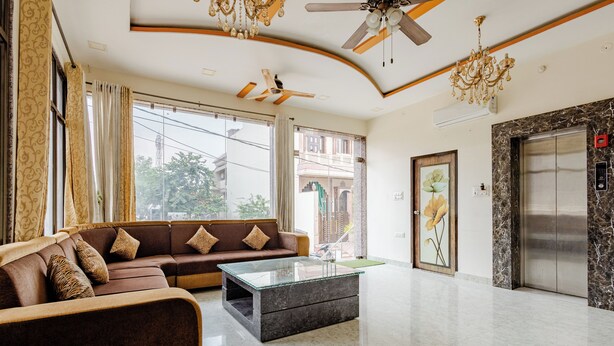 A modern living room with a brown sofa, a glass coffee table, and a ceiling fan. - The Tiger Heritage  (Sawai Madhopur)