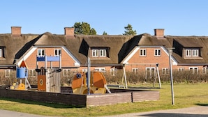 Un parque infantil con estructuras de juego y un edificio de ladrillo al fondo.