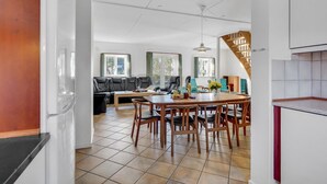 Una cocina moderna con comedor, una escalera y una sala de estar con sofá y mesa de centro.