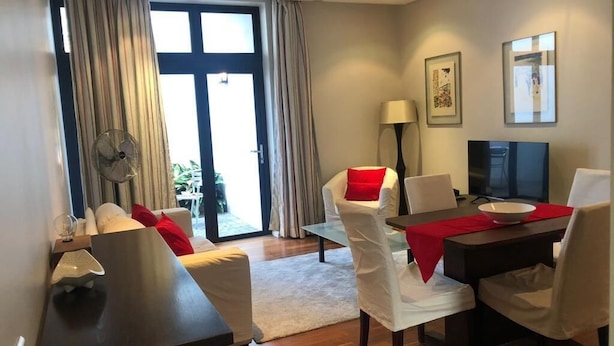 Ein modernes Hotelzimmer mit Essbereich, Fernseher und großem Fenster mit Vorhängen.