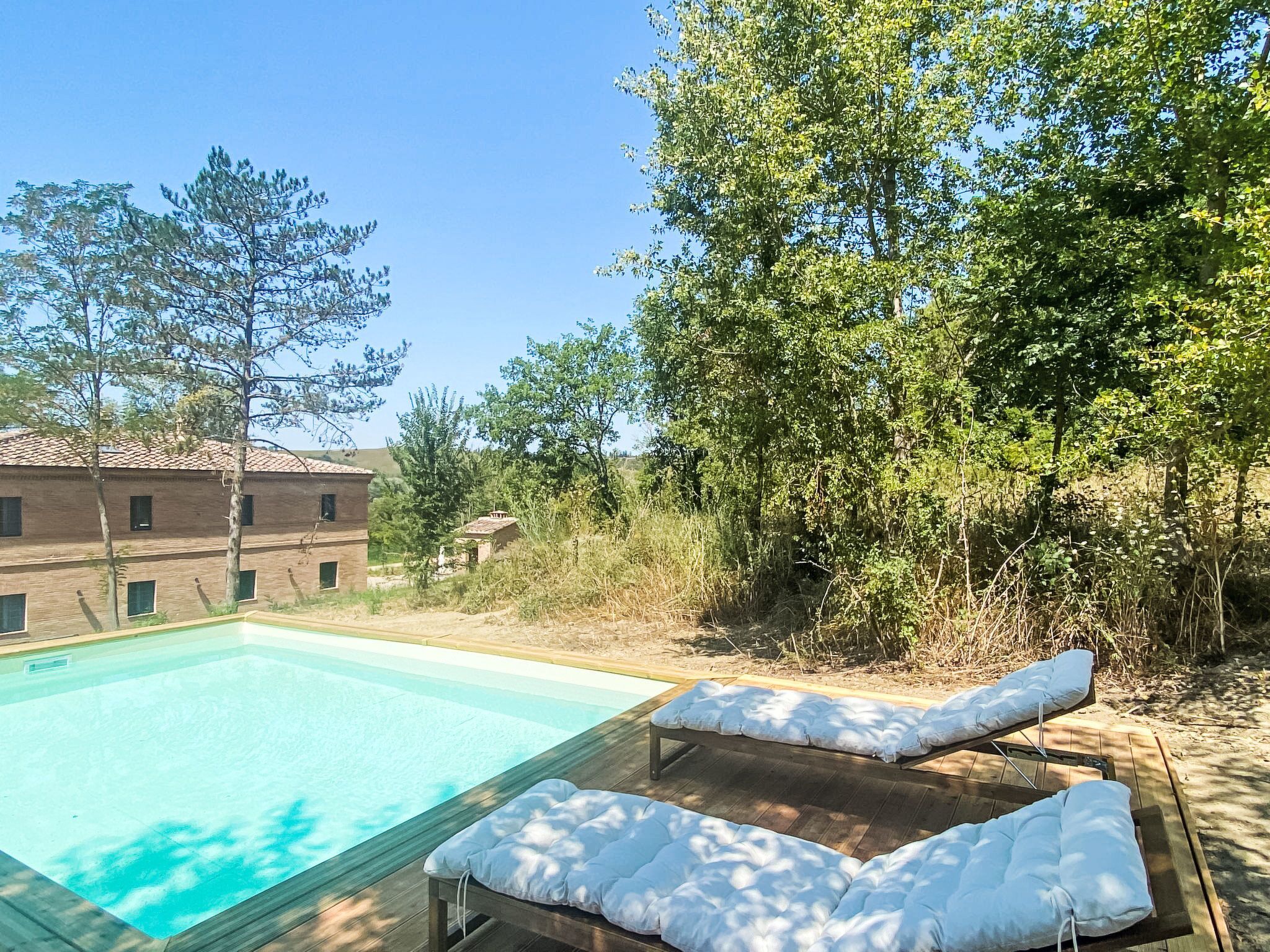 Ein Pool mit zwei Liegestühlen und einem Gebäude im Hintergrund.