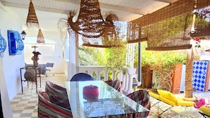 Un suelo a cuadros, una mesa de cristal y una silla negra en una habitación con techos altos y lámparas de mimbre colgantes.