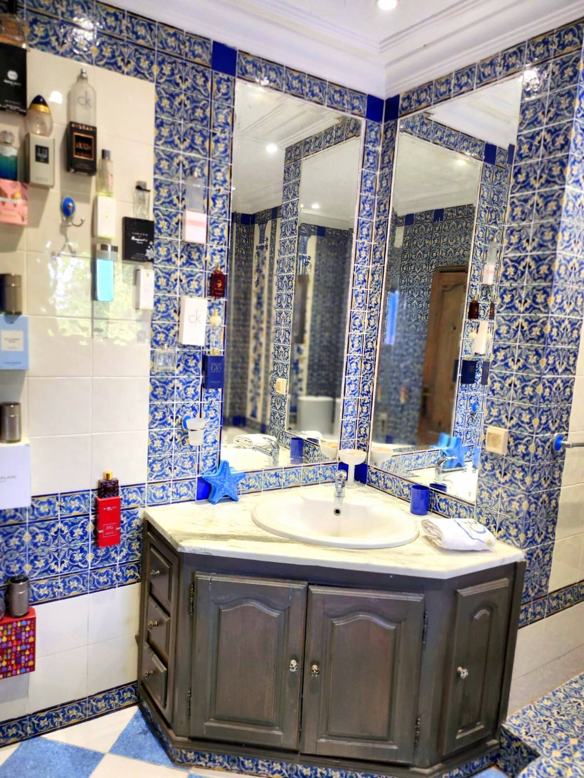 A bathroom with a large mirror, a sink, and a cabinet.