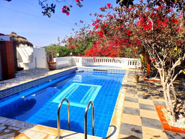 A swimming pool with tiled edges and a checkered pattern around it.