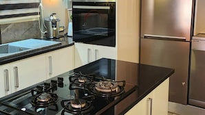 Una cocina moderna con una isla central, horno empotrado, refrigerador de acero inoxidable y microondas.