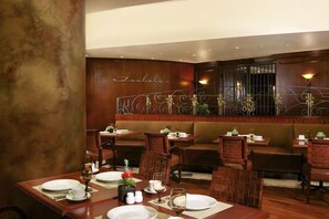 Un restaurant aux murs en bois, agrémenté d’une rampe décorative en métal et dont les tables sont dressées pour le service.