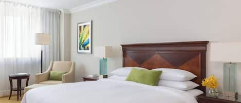 Une chambre d’hôtel avec un grand lit, une chaise, une table de chevet, une lampe et un vase rempli de fleurs.
