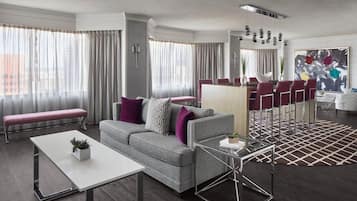 A modern living room with a grey sofa, white coffee table, and a patterned rug.