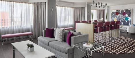 Un salon moderne avec un canapé gris, une table basse blanche et un tapis à motifs.