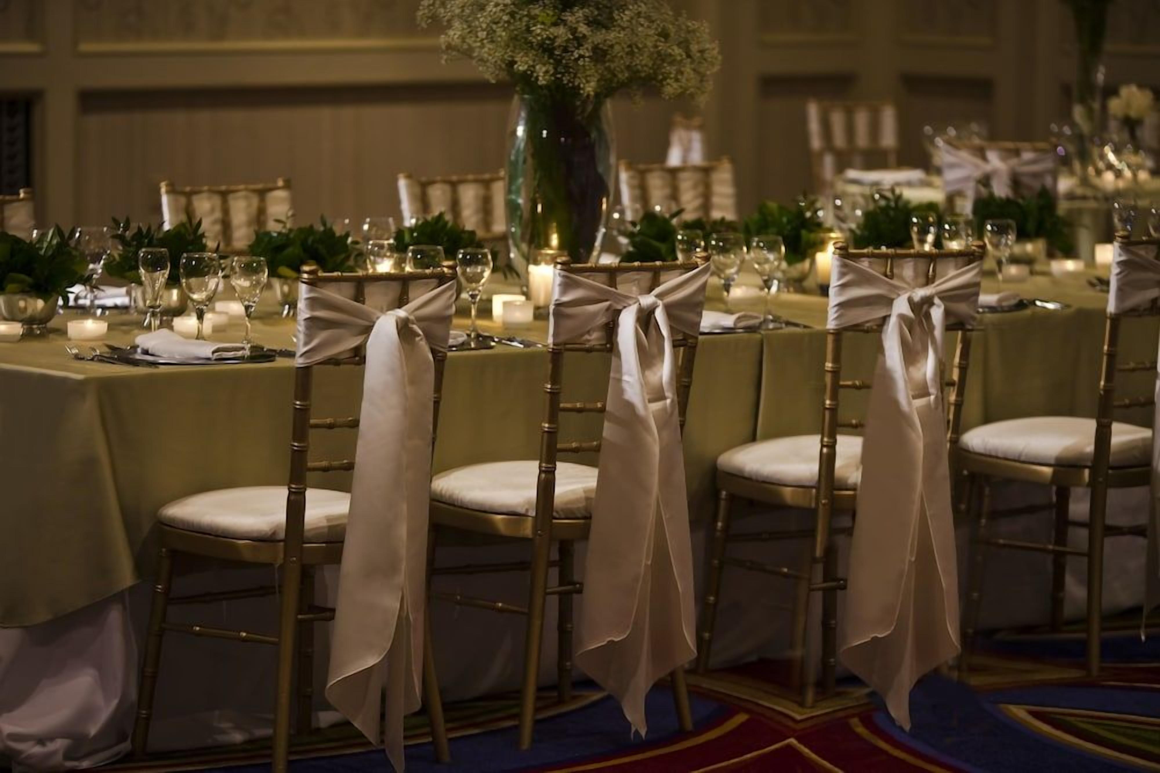 A banquet table set with chairs, candles, and floral centerpieces.