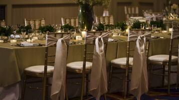 A banquet table set with chairs, candles, and floral centerpieces.