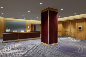 A reception area with a reception desk, a large wooden column, and a carpeted floor.