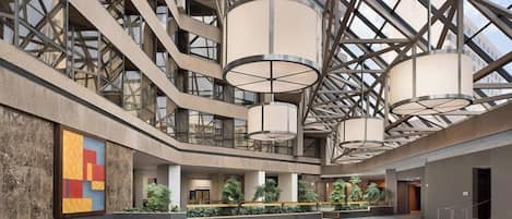 A spacious atrium with a high ceiling, large windows, and hanging lamps.