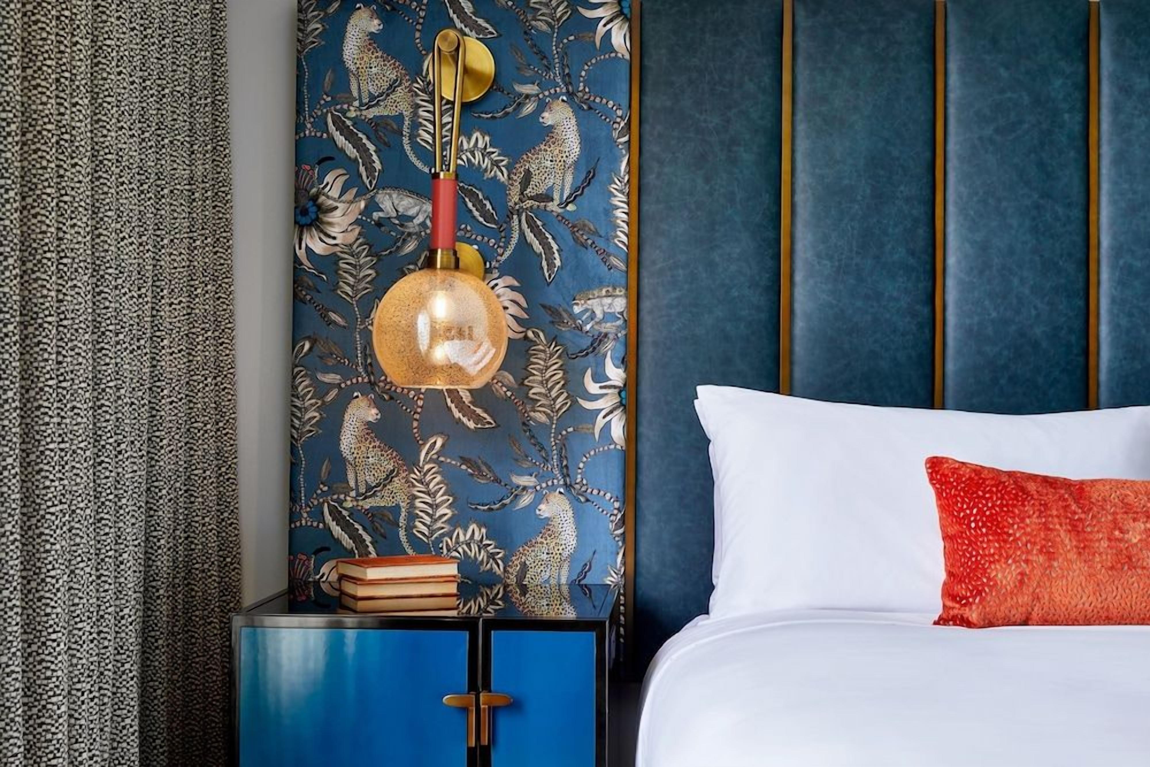 A bedroom with a bed, a nightstand with a lamp, and a blue cabinet.