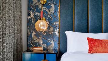 A bedroom with a bed, a nightstand with a lamp, and a blue cabinet.
