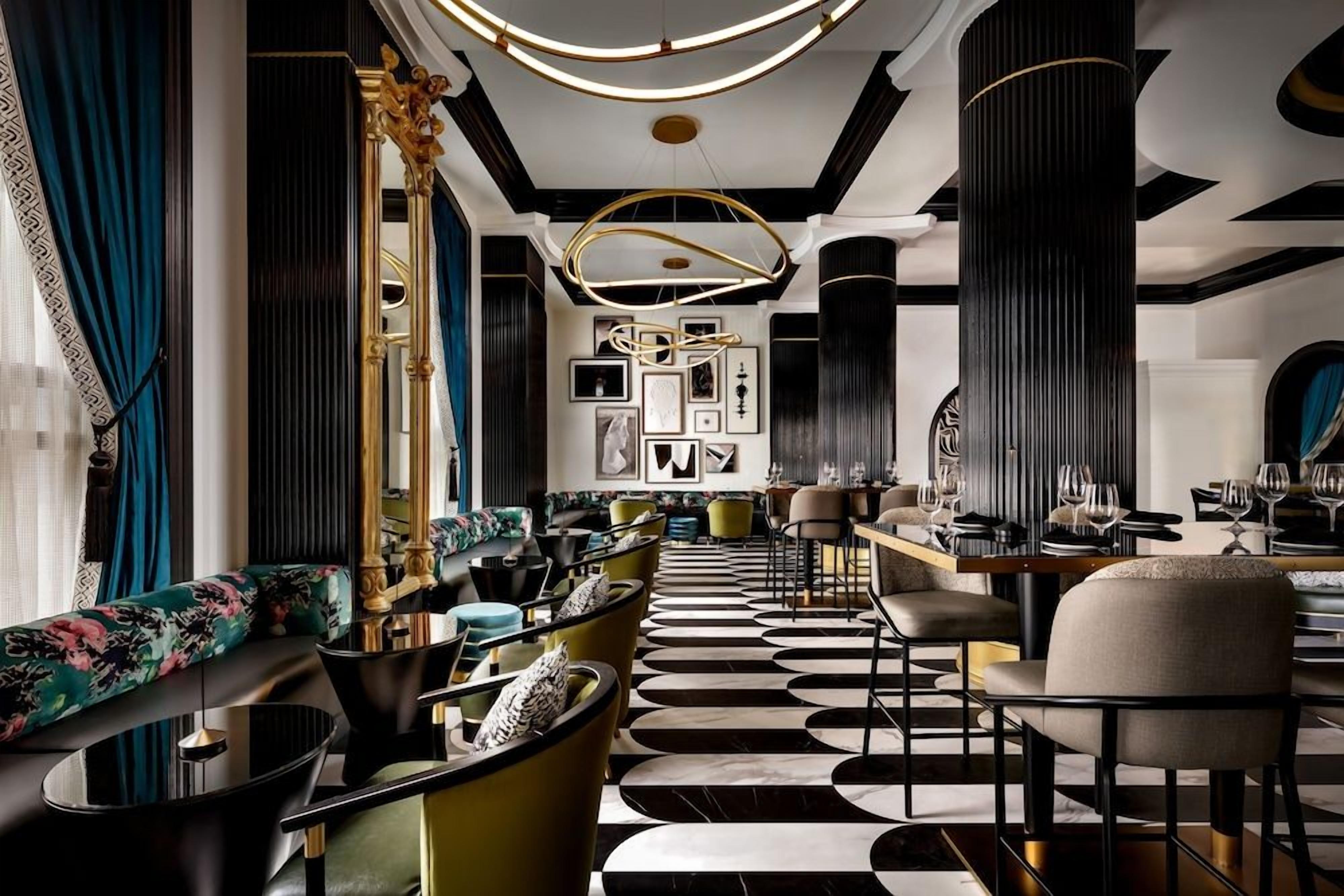 A modern interior with a black and white patterned floor, a seating area with sofas and armchairs, and a bar area with tables and chairs.