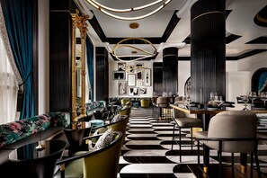 A modern interior with a black and white patterned floor, a seating area with sofas and armchairs, and a bar area with tables and chairs. - 2 Connecting Suites at a 4.5⭐️ Hotel (Orlando)