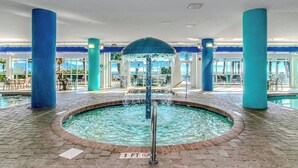 An indoor pool area with a central water feature, surrounded by blue pillars and a tiled floor. - 1BR Direct Ocean Front Suite Newly Renovated! (Myrtle Beach)
