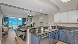 A modern kitchen with a central island, a dining area with a view, and a balcony with a view. - 1BR Direct Ocean Front Suite Newly Renovated! (Myrtle Beach)