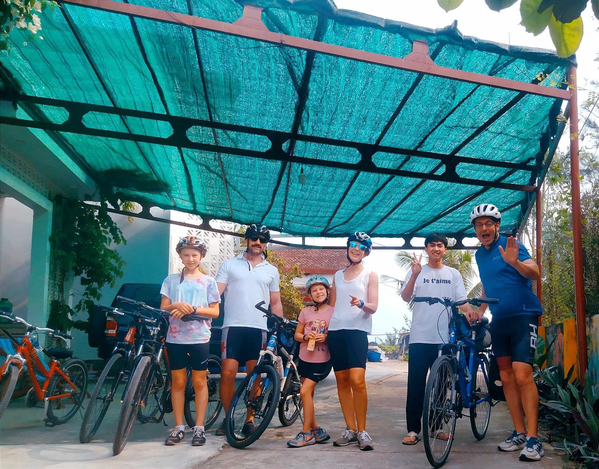 A group of people standing under a green canopy with bicycles.