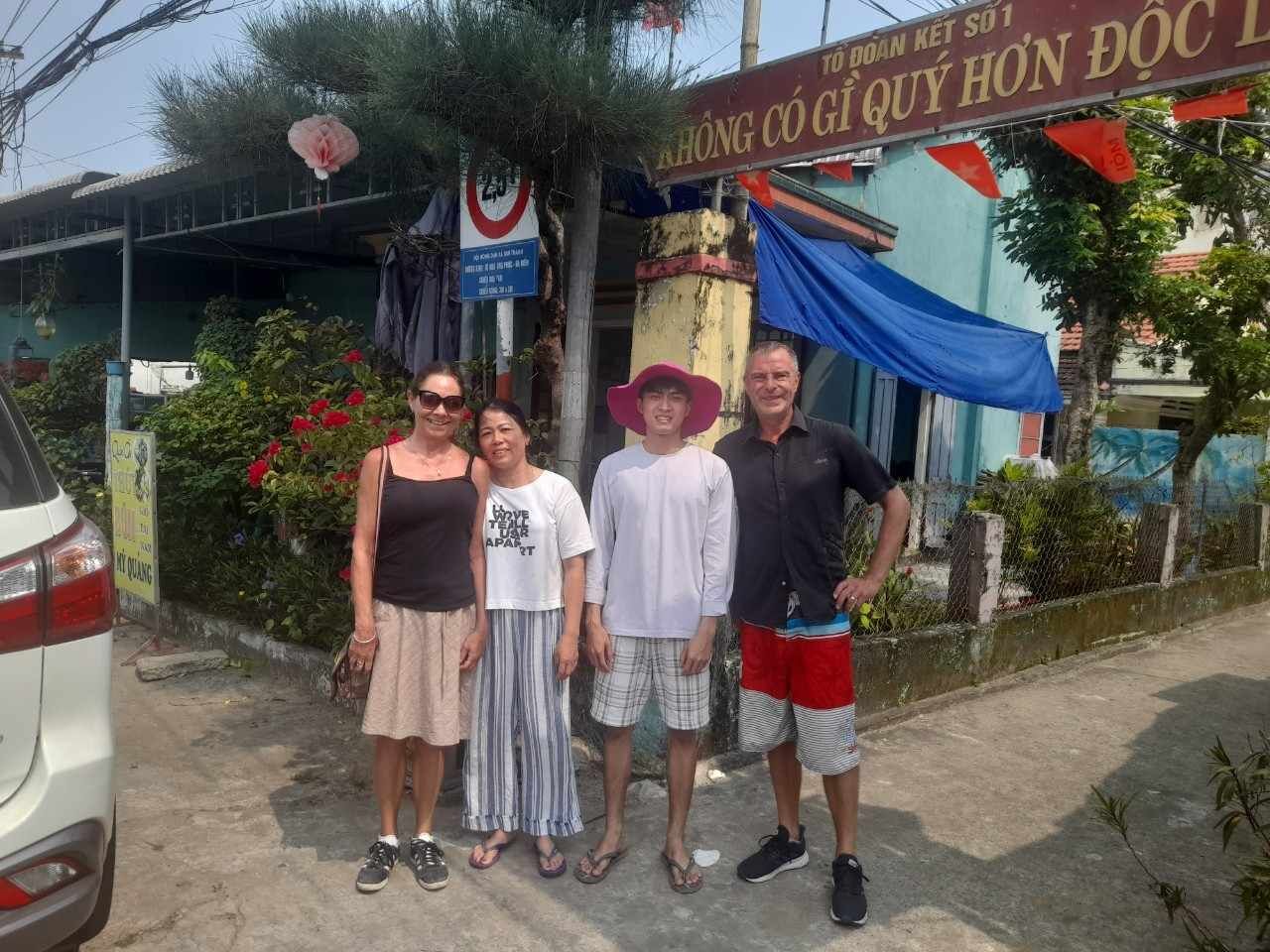 A group of people standing in front of a building with a sign that reads "TOI DAO KET SOI."