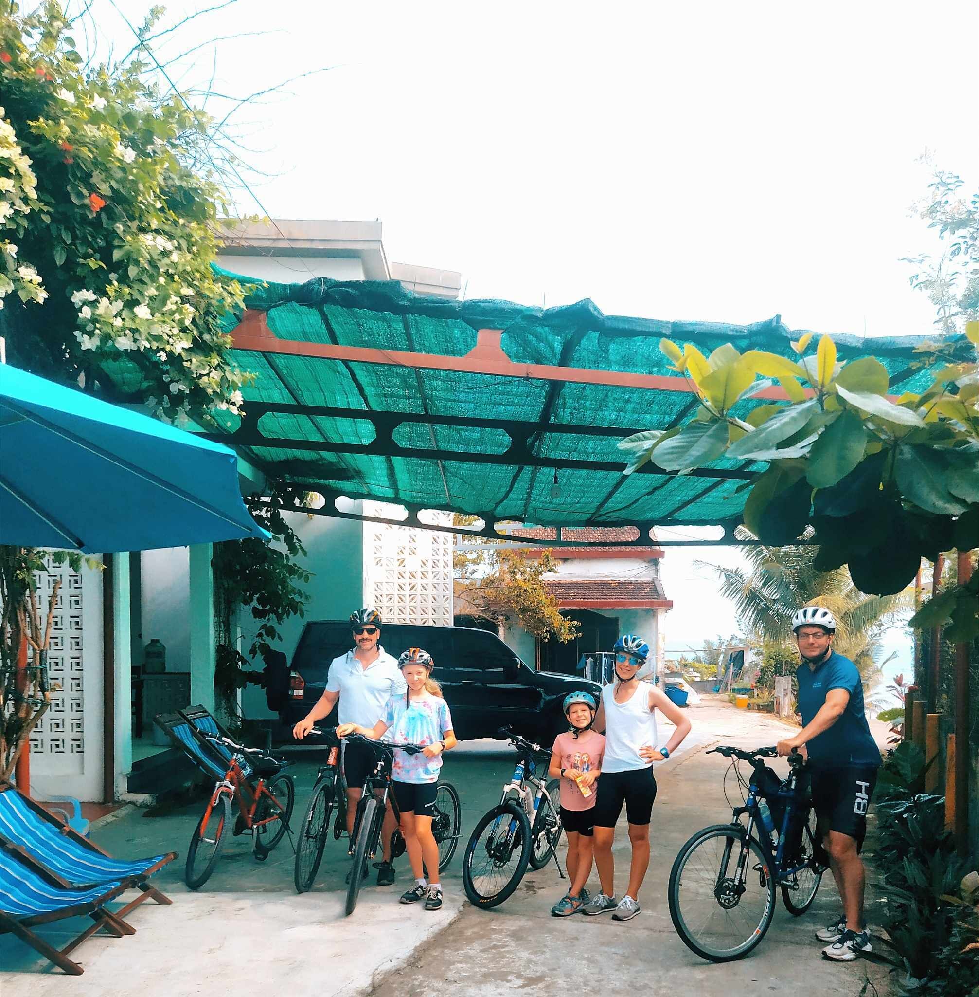 Un espacio exterior techado con bicicletas, un coche y un edificio con tejado verde.
