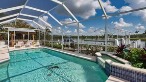 Un espace piscine doté d’une structure couverte, de chaises longues et offrant une vue sur l’eau.
