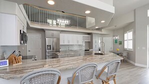 Une cuisine spacieuse avec un îlot en marbre, un plafond haut et un balcon.
