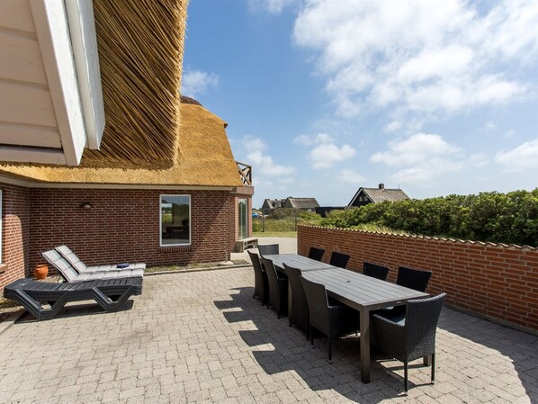 Eine Terrasse mit Backsteinmauer, Tisch und Liegestühlen.