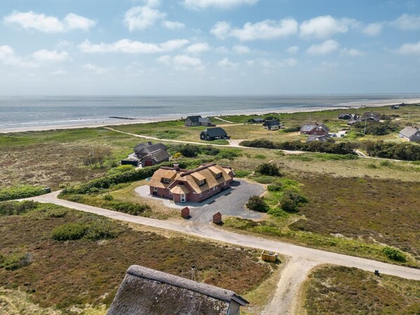 Ein Küstengebiet mit mehreren Häusern, freiem Blick auf den Strand und einer unbefestigten Zufahrt.