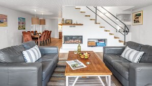 Ein modernes Wohnzimmer mit zwei grauen Sofas, einem Holztisch und einer Treppe mit Holzstufen.