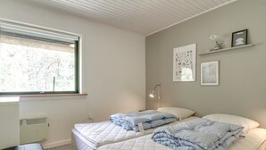 A bedroom with two beds, a desk, and a window.