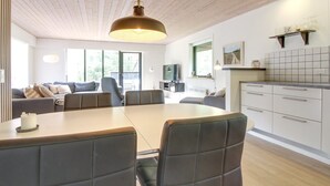 A modern living room with a dining table, sofas, and a TV.