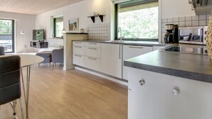 A modern kitchen with white cabinets, a large window, and a built-in oven.