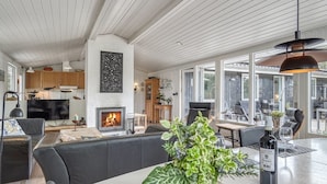 En moderne stue med pejs, siddepladser og store vinduer.
