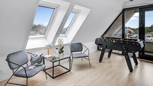 Moderni loft-tyylinen asunto, jossa on korkeat katot, kattovalokuviot, pöytäjalkapallo ja näkymä kaupunkiin.
